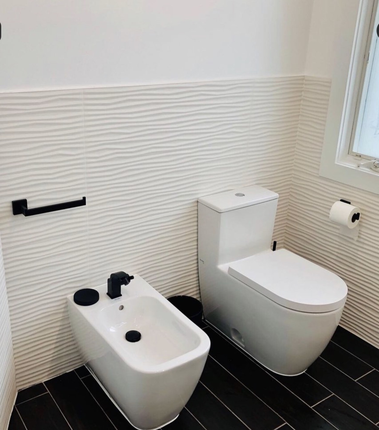 Powder room with bidet, wall-hung toilet and textured tile wall
