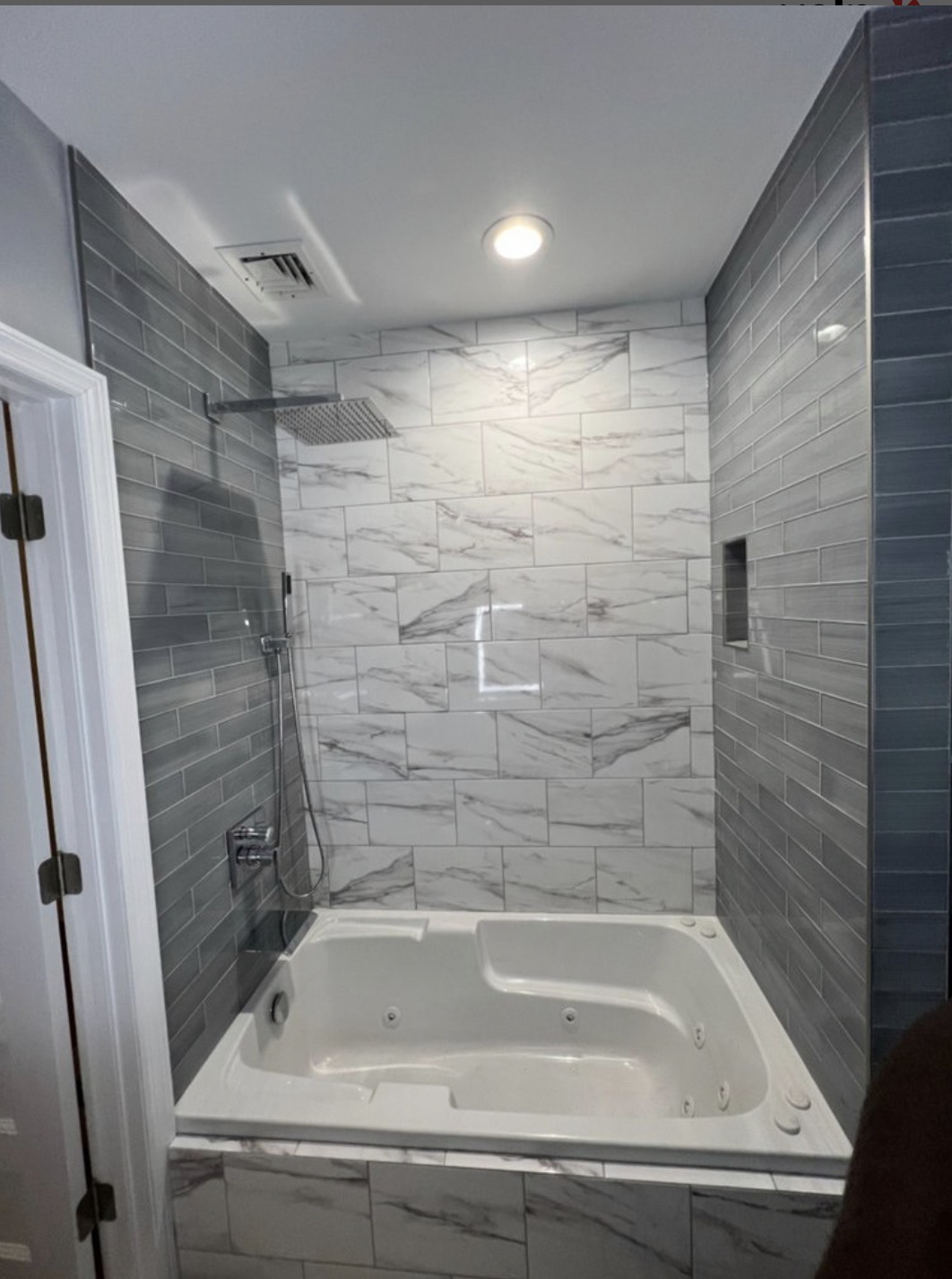 Primary bathroom with marble tile shower surround and jetted soaking tub