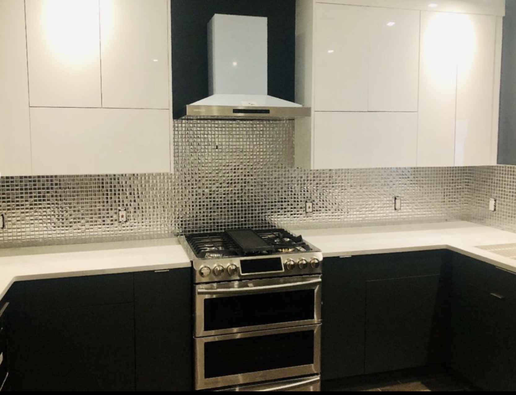 Kitchen with two-tone cabinetry and mosaic tile range backsplash