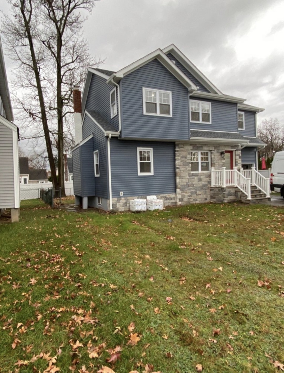Two-story home exterior with blue vinyl siding and stone veneer accents